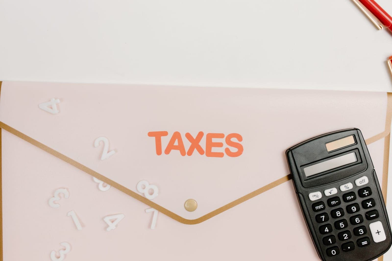 Calculator resting beside a folder labelled Taxes, representing how importers calculate customs duty and sales tax in Pakistan