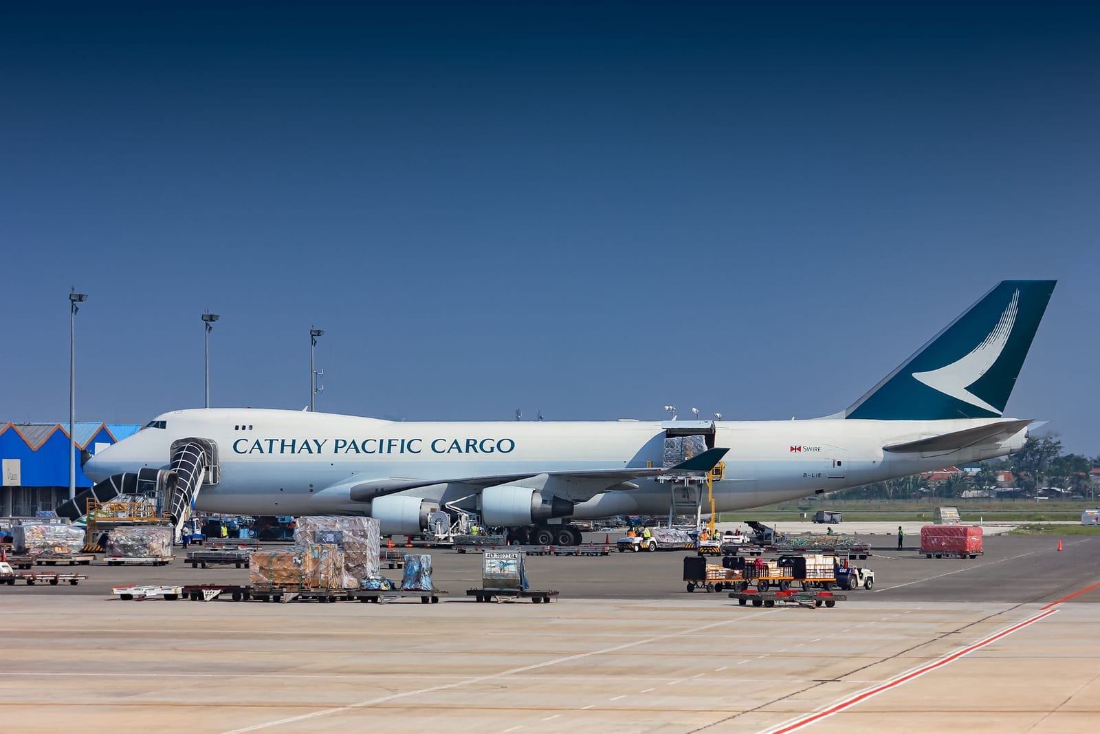 Cargo freighter aircraft being loaded on the airport tarmac, representing air freight as a faster alternative to sea freight