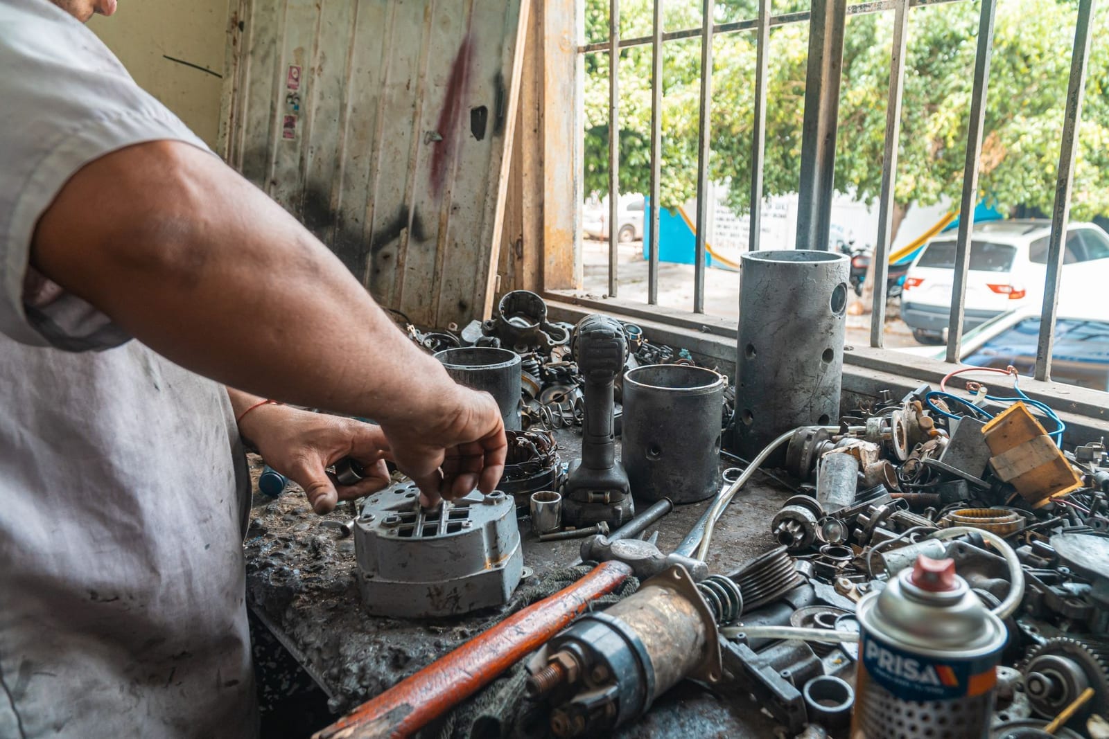 Technician's hands examining automotive parts laid out on a workshop table, representing car parts imported into Pakistan