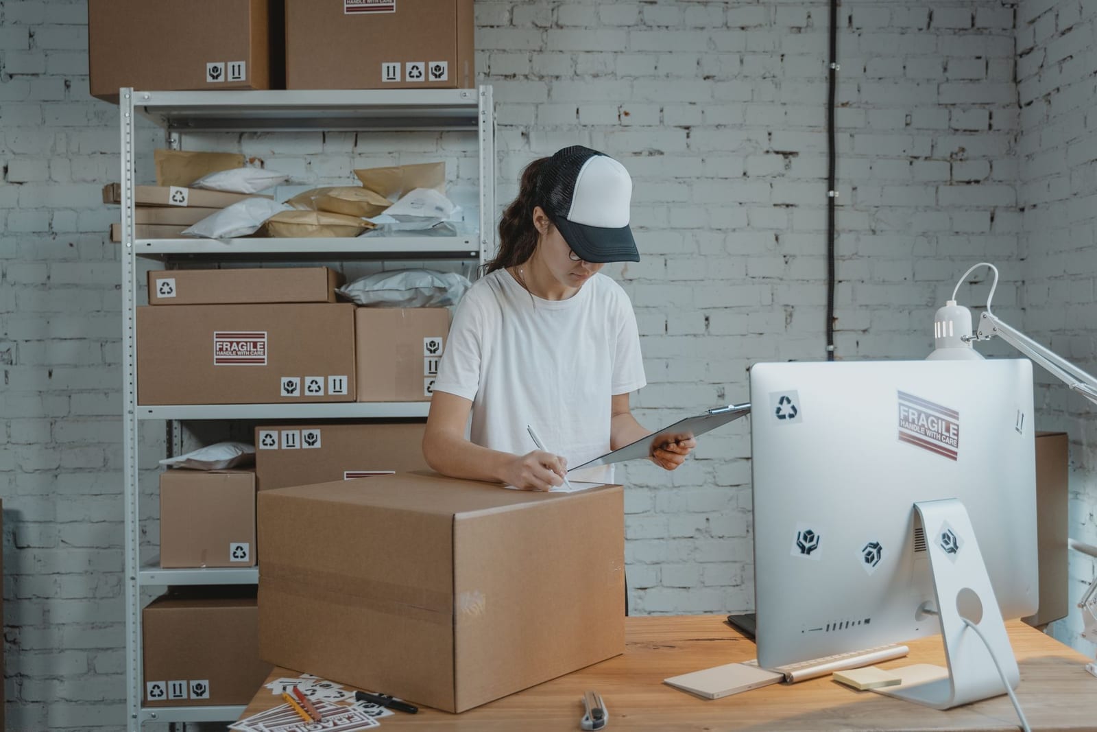 Small business owner reviewing a shipment checklist beside packed parcels, representing e-commerce import logistics keeping online retail stocked in Pakistan