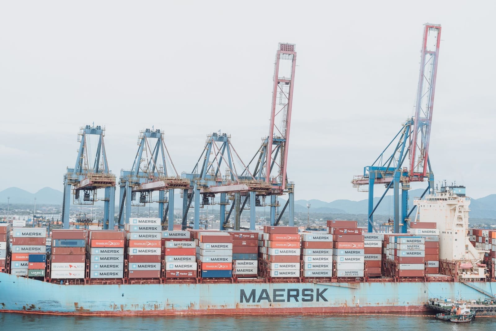 Container vessel being loaded by overhead gantry cranes at a commercial port terminal, representing export customs clearance in Pakistan