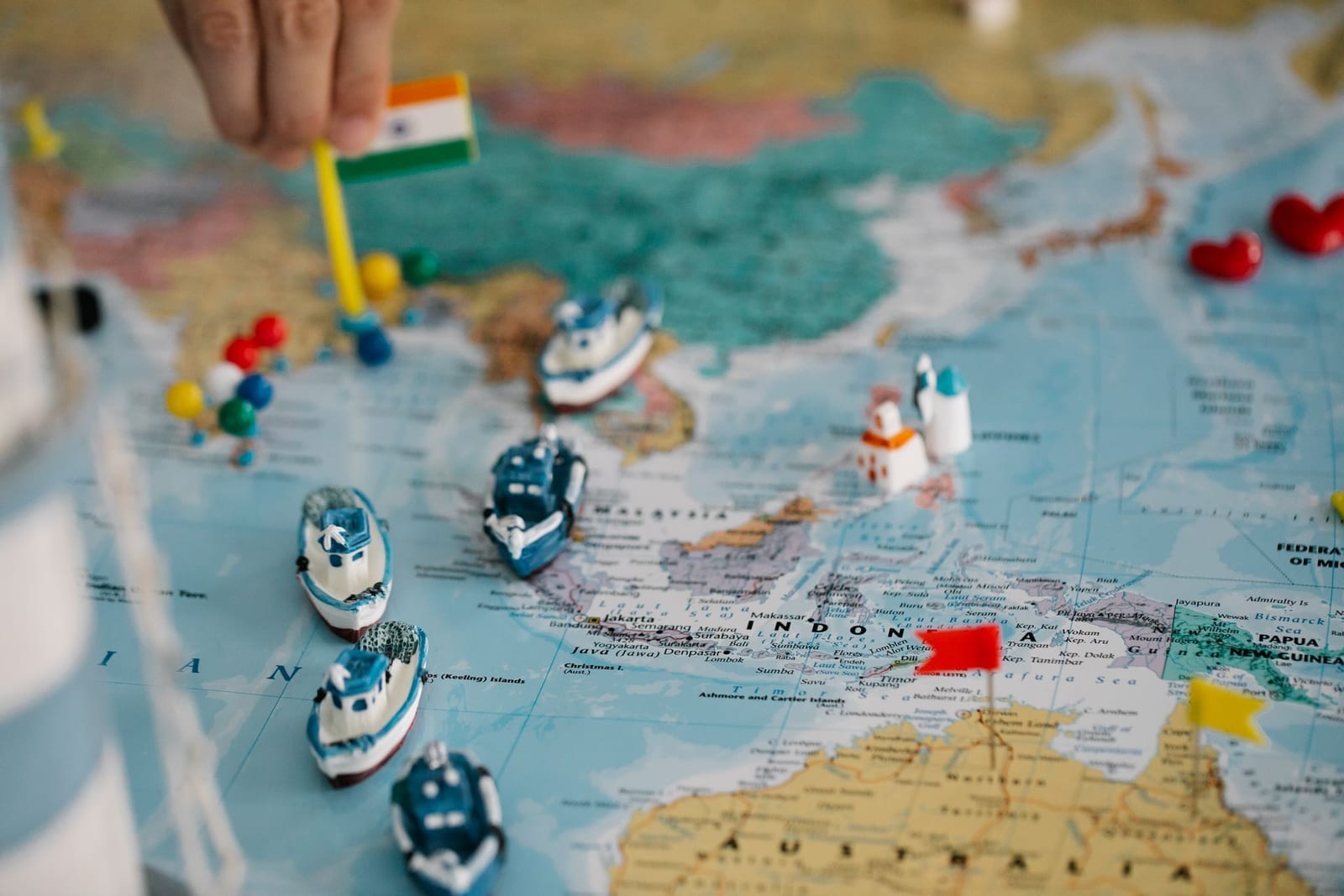Miniature cargo ships and flag markers placed across a world map, representing Incoterms 2020 risk-transfer points for Pakistani importers