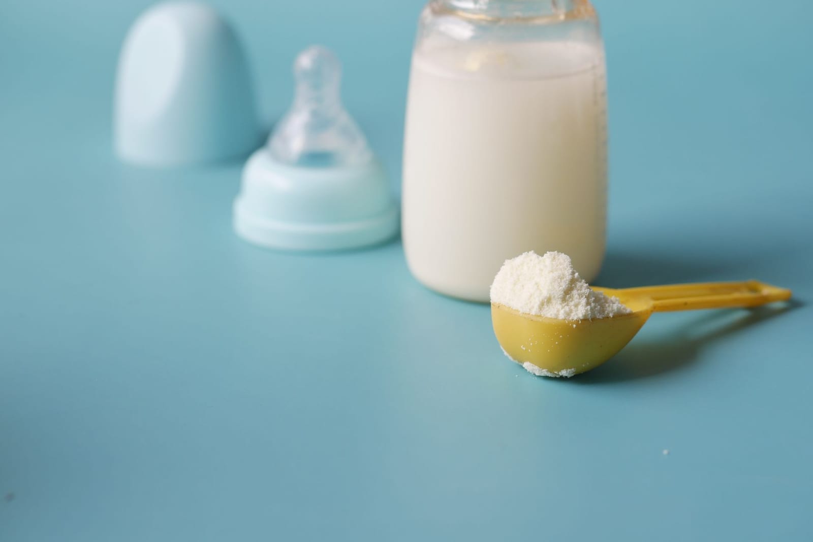 Milk powder piled in a measuring scoop beside a feeding bottle, representing milk powder and food imports cleared through Pakistan's food standards desk